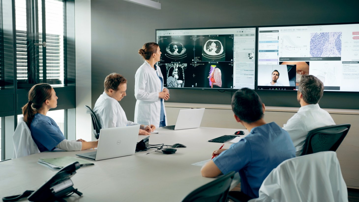 Physicians engaged in a meeting, viewing a presentation and conducting a video conference call