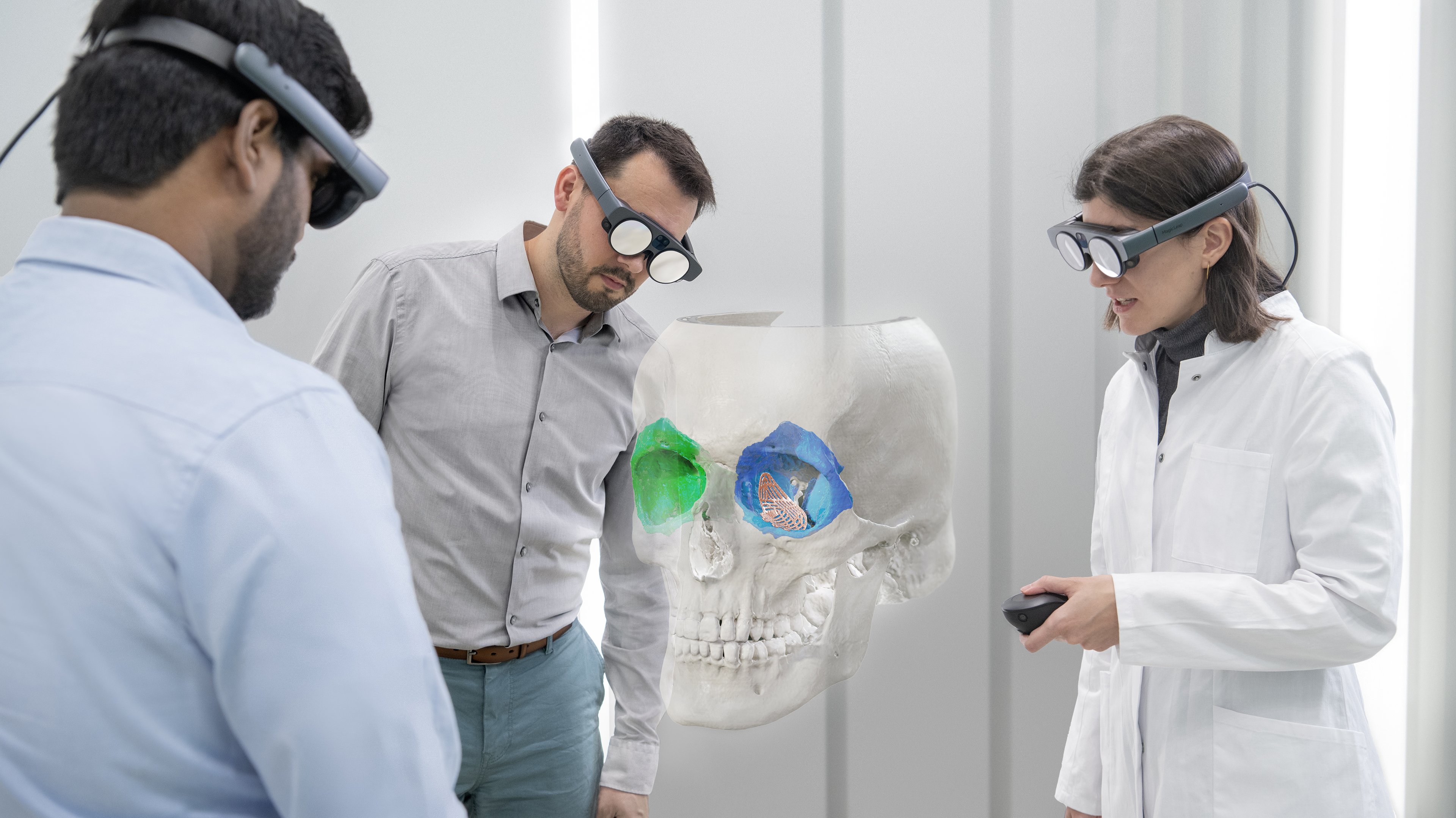 Brainlab's Mixed Reality Viewer in use, featuring three individuals in an office setting examining a cranial image