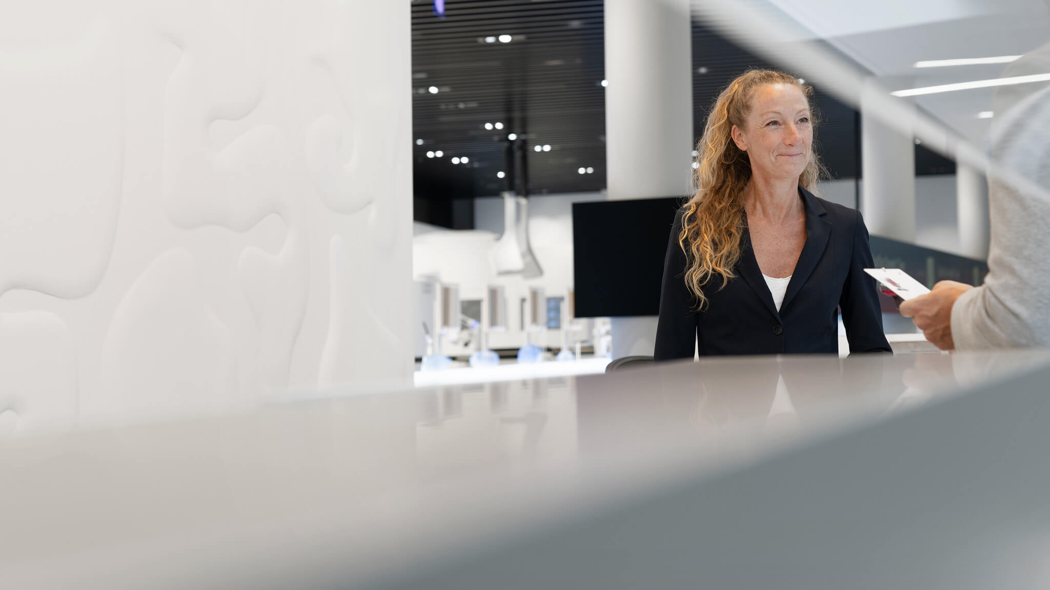 The receptionist is standing behind the front desk at the headquarters in Munich